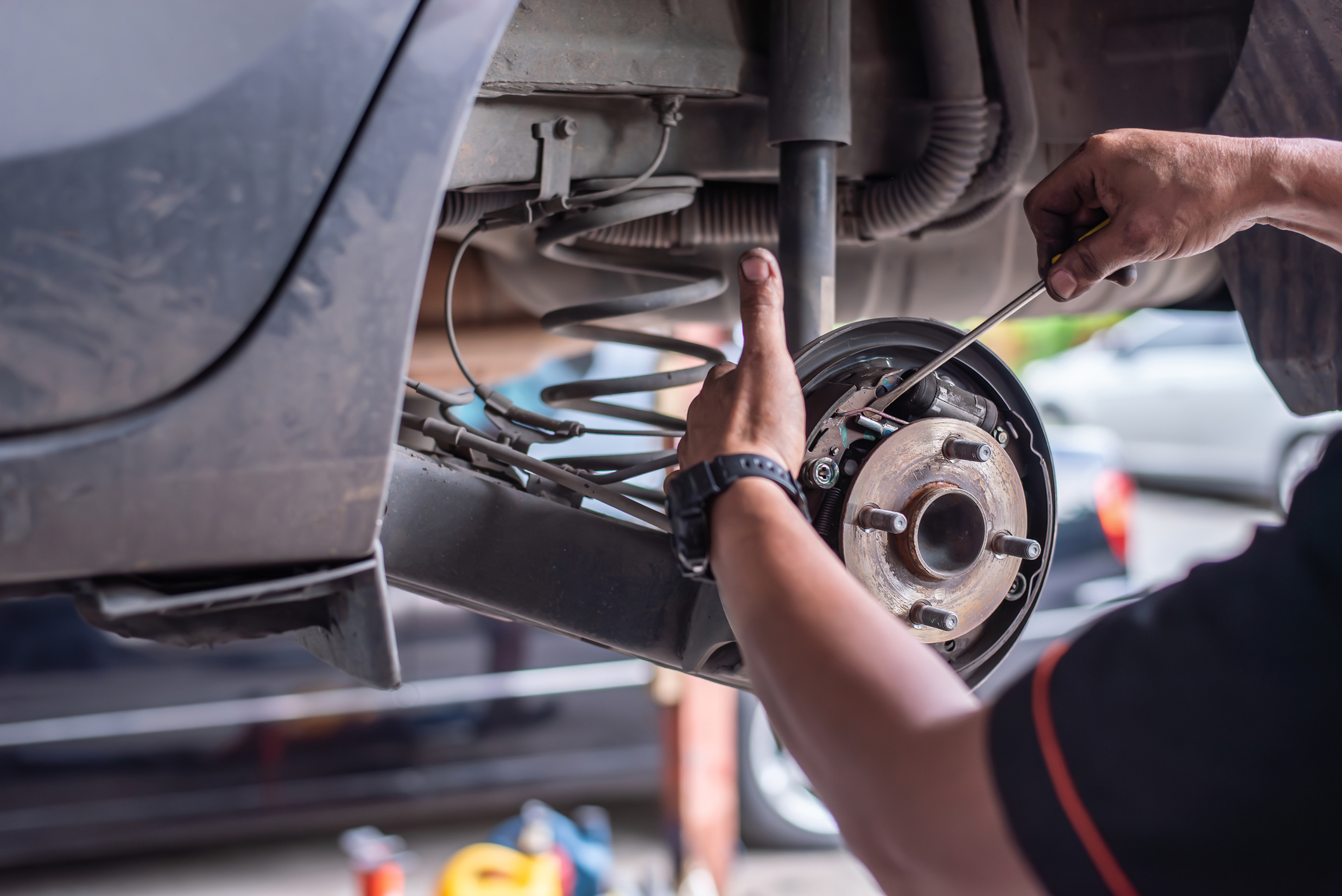 A mechanic works on the brake system of a vehicle in a garage, focusing on maintenance and repair of car brakes.