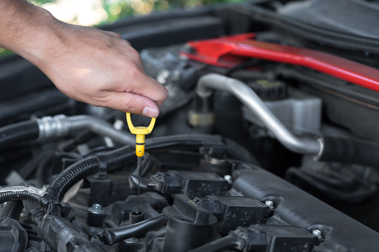 Mechanic repairing car with open hood, Engine oil filling