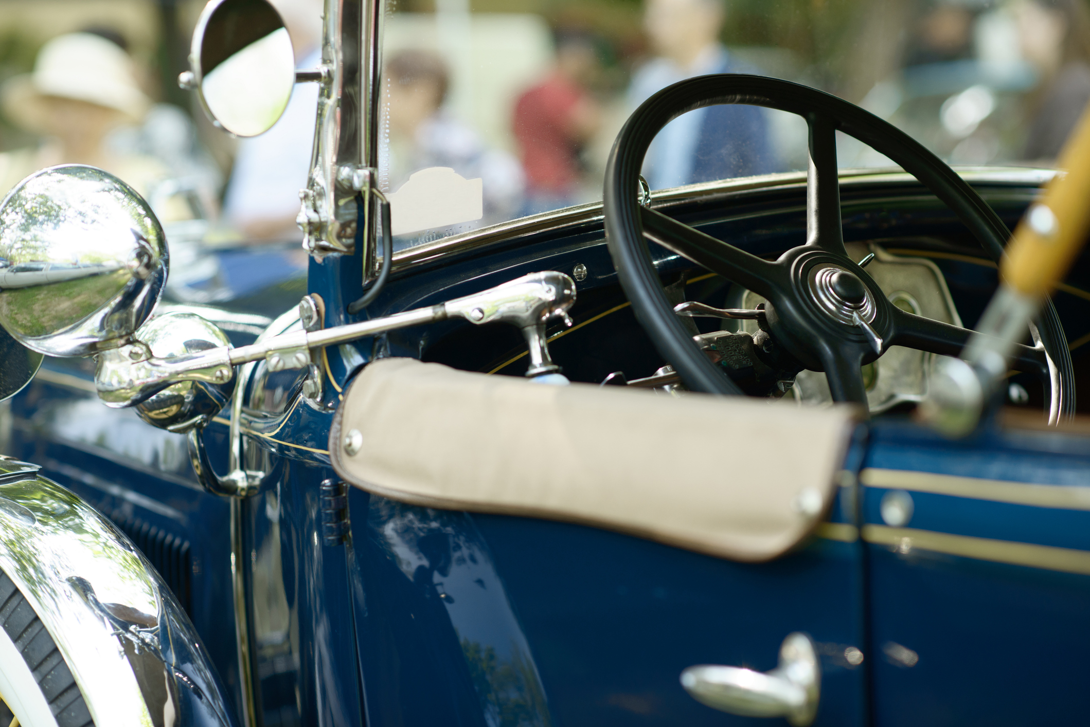 Classic vintage car interior with steering wheel, chrome mirror and open roadster cockpit.